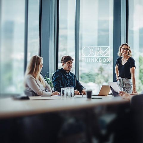 Sanal ThinkBox alanında bir masa etrafında sohbet eden bir grup insan.