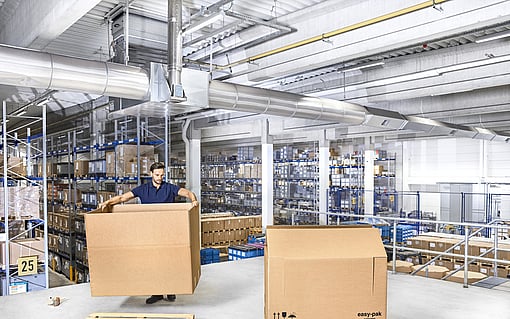 Ağır yükler için oluklu mukavva kutu monte eden bir kişi.