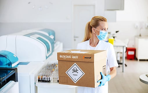Tehlikeli madde içeren bir oluklu mukavva kutu taşıyan bir kadın.