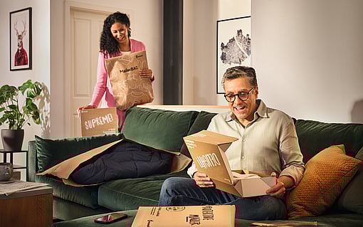 Bir erkek ve bir kadın oturma odalarında, SupremeBox, Delight ve Protective Mailer gibi Mondi eCommerce ambalaj ürünleriyle çevrililer.