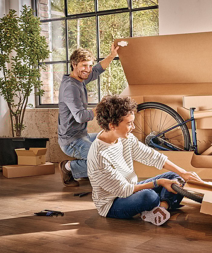 Mondi Bike Packaging Solutions'ın ürettiği bir bisikleti kutudan çıkaran bir adam ve bir çocuk