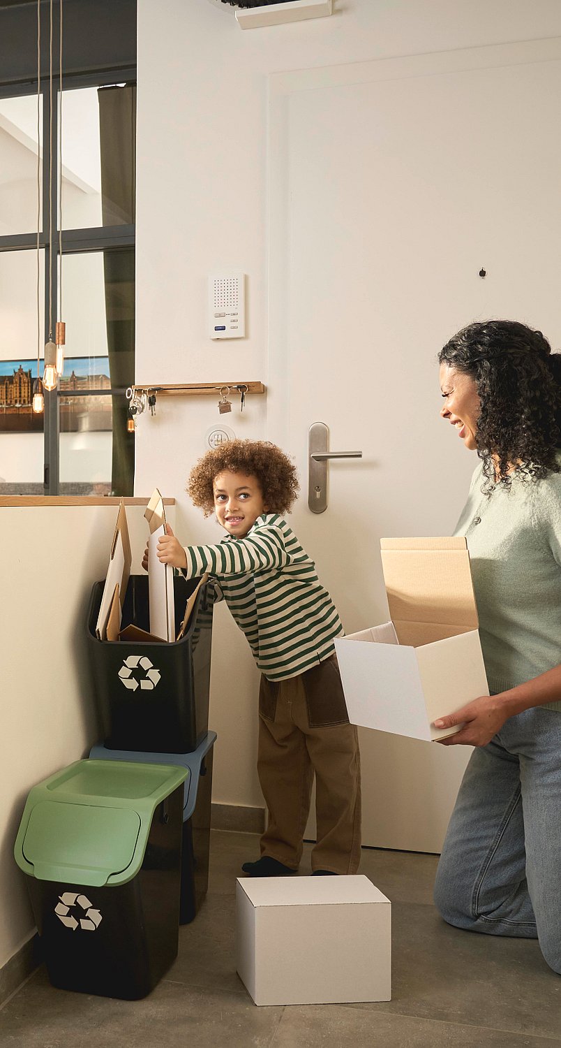 Bir anne ve çocuğu geri dönüşüm kutularını topluyor.