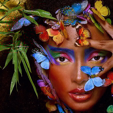 Canlı yapraklar ve kelebeklerle çevrili bir kadın.