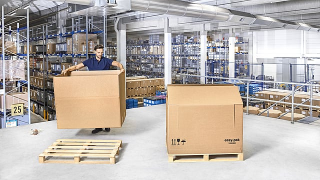 Ağır yükler için oluklu mukavva kutu monte eden bir kişi.