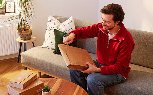 Bir paket açmak için yırtma şeridi kullanan bir adam.